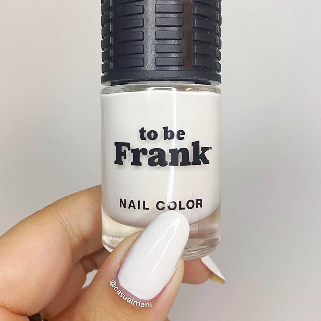 A hand holds bottle of To Be Frank white nail polish named Bleach