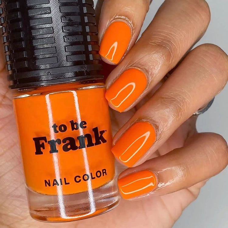 To Be Frank orange nail polish bottle with manicured hand